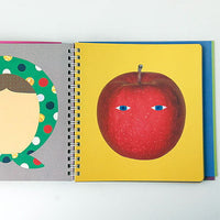 Spiral-bound book with illustrations of a face and an apple on a white background